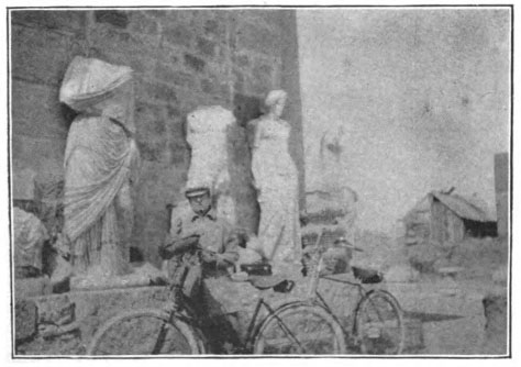 man with bikes standing in front of Greco-Roman statues